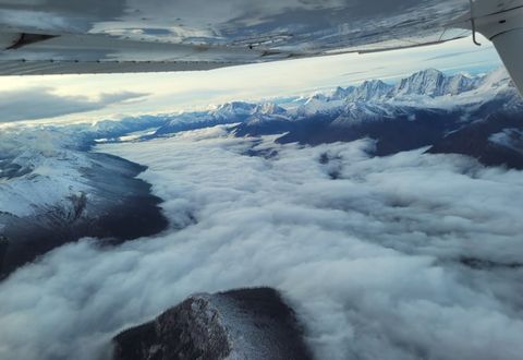 Cloud filling a mountain valley below snowy peaks