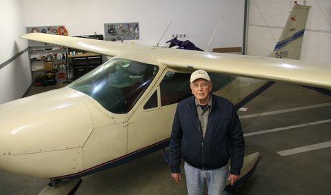 Bill Keen standing beside his cream 1968 Cessna Cardinal, C-GVBR, in its hangar