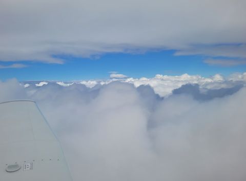Cloud tops below the wing, with a band of blue sky above